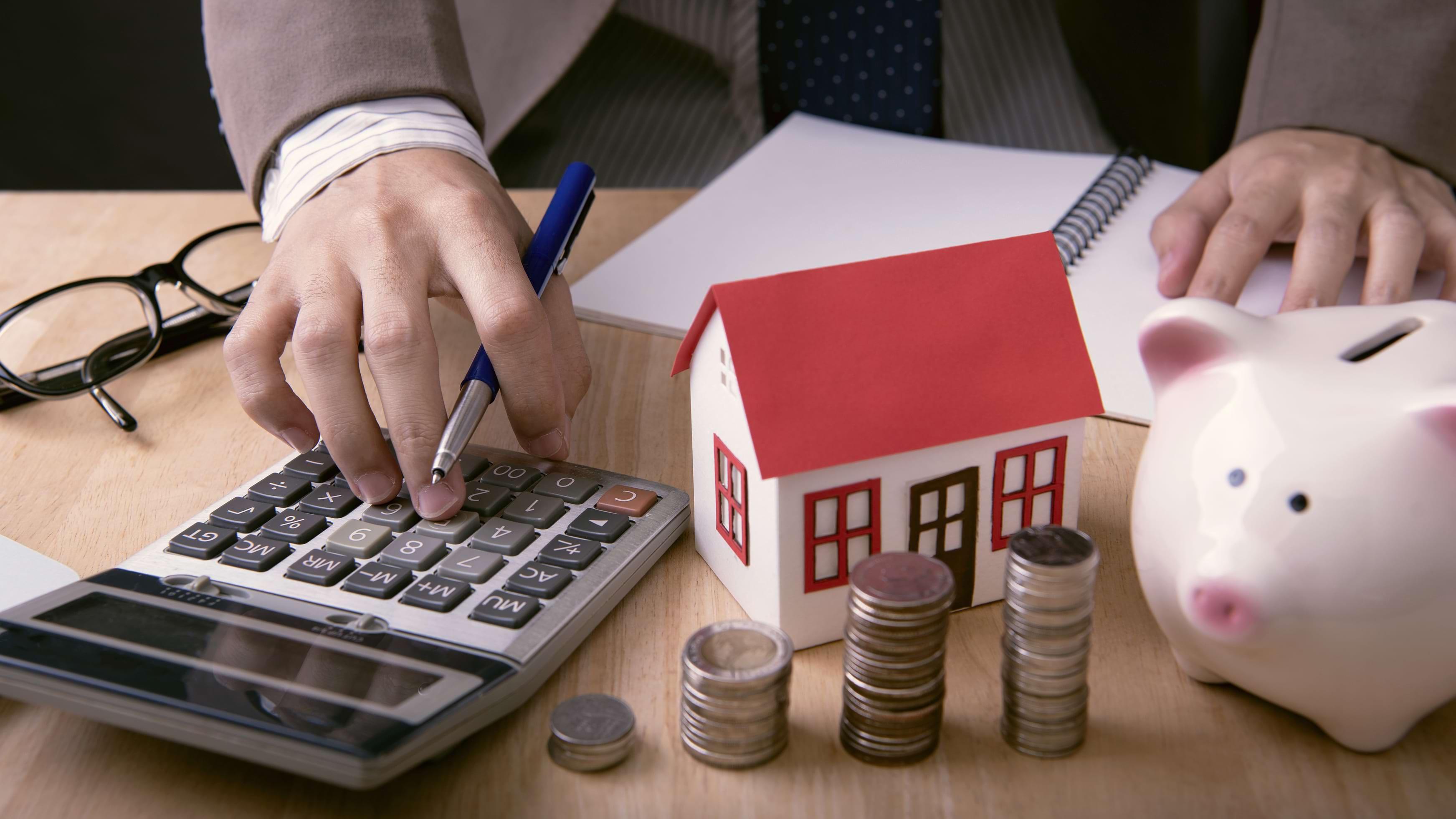 Male accountant with calculator, note pad, and small piles of coins